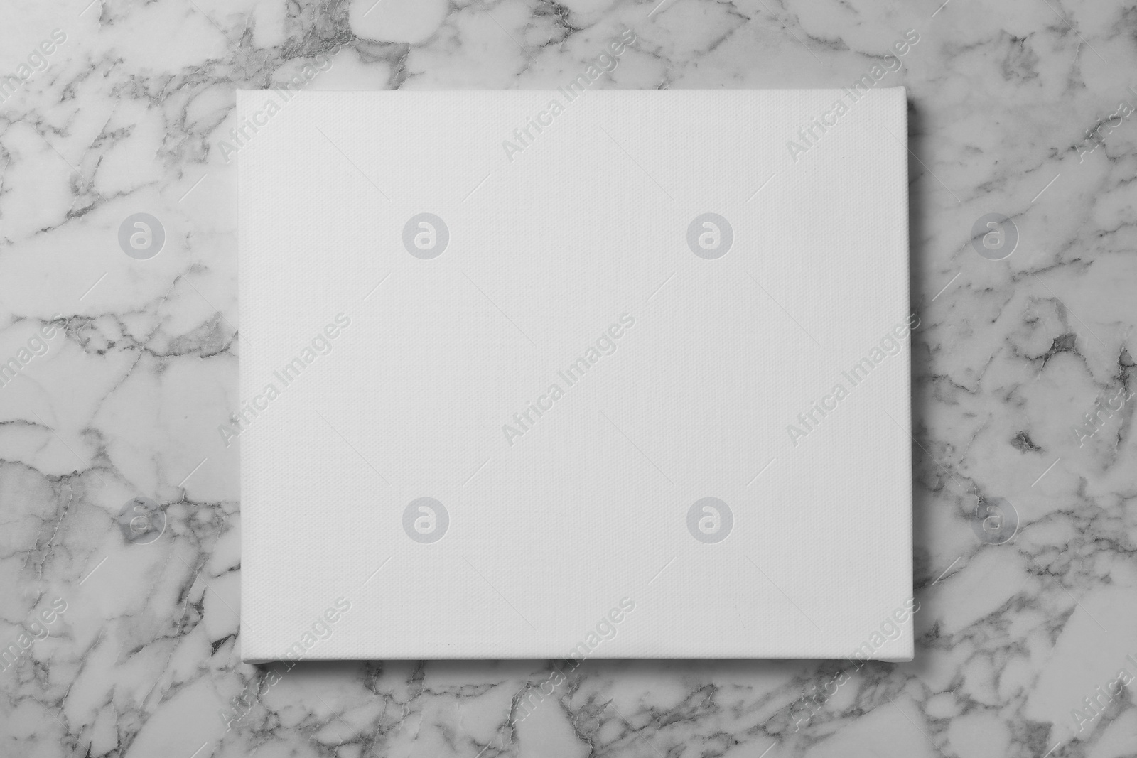 Photo of Blank canvas on white marble background, space for text