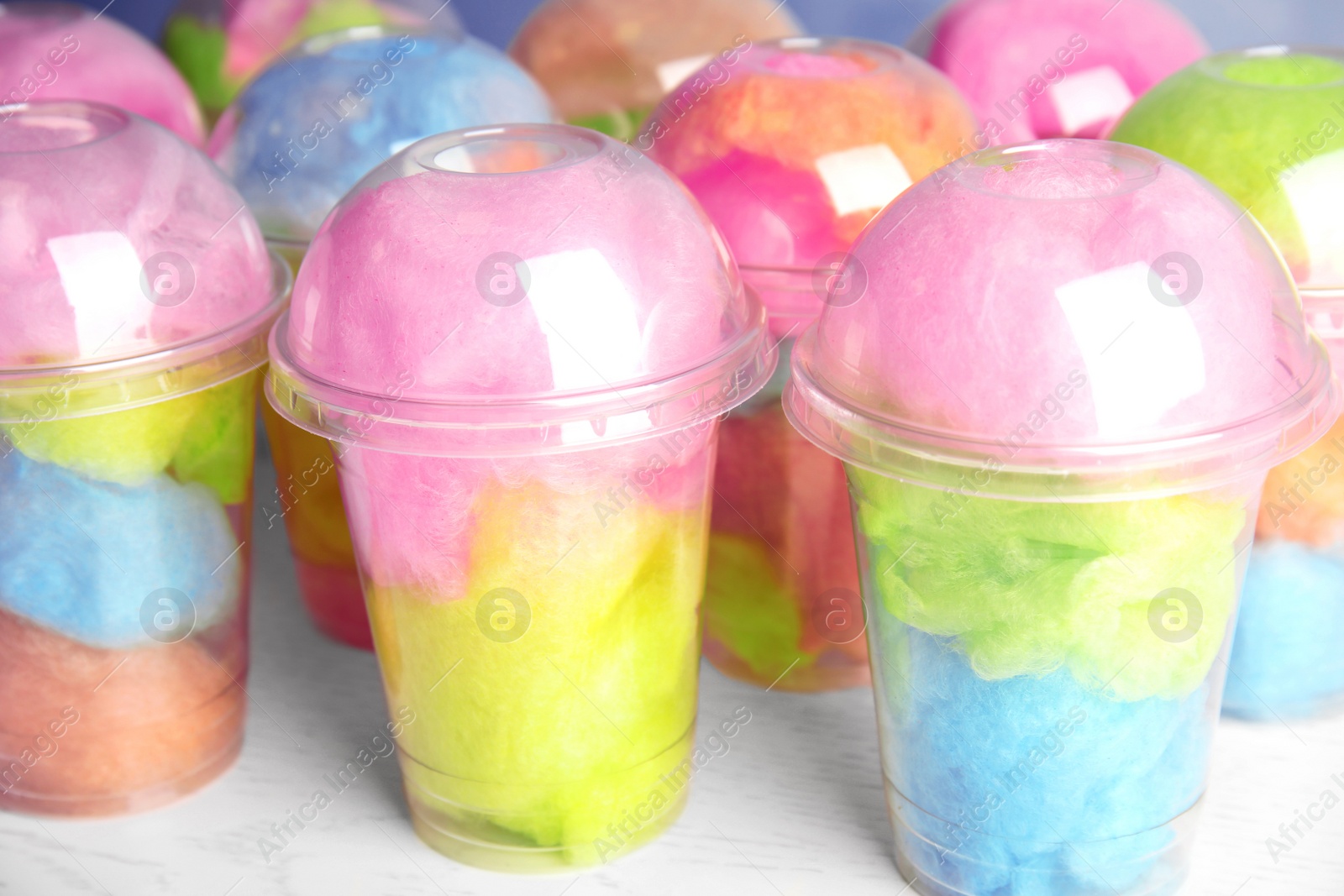 Photo of Many plastic cups with tasty cotton candies on white wooden table