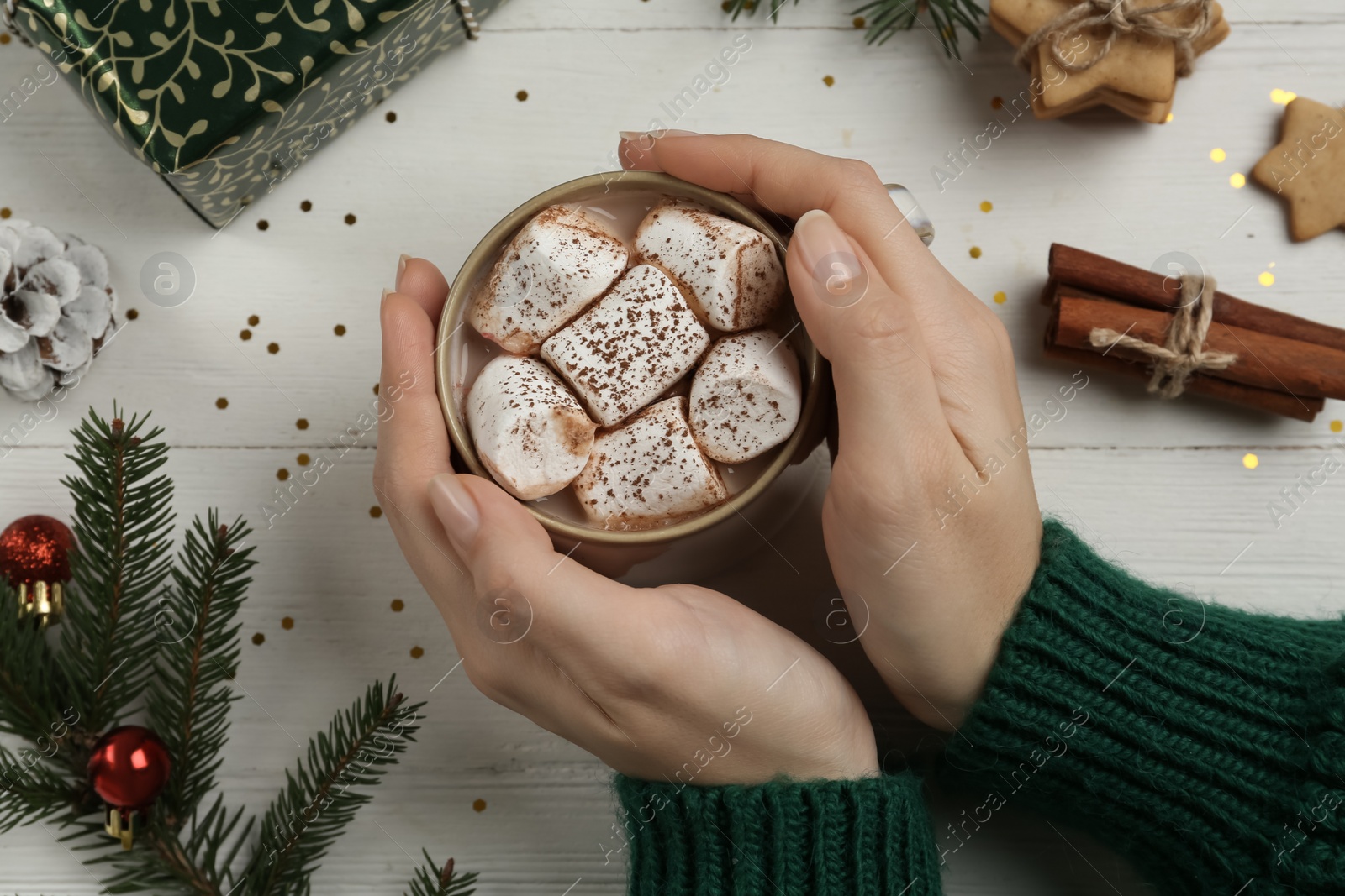 Photo of Woman with cup of delicious marshmallow cocoa at white wooden table, top view