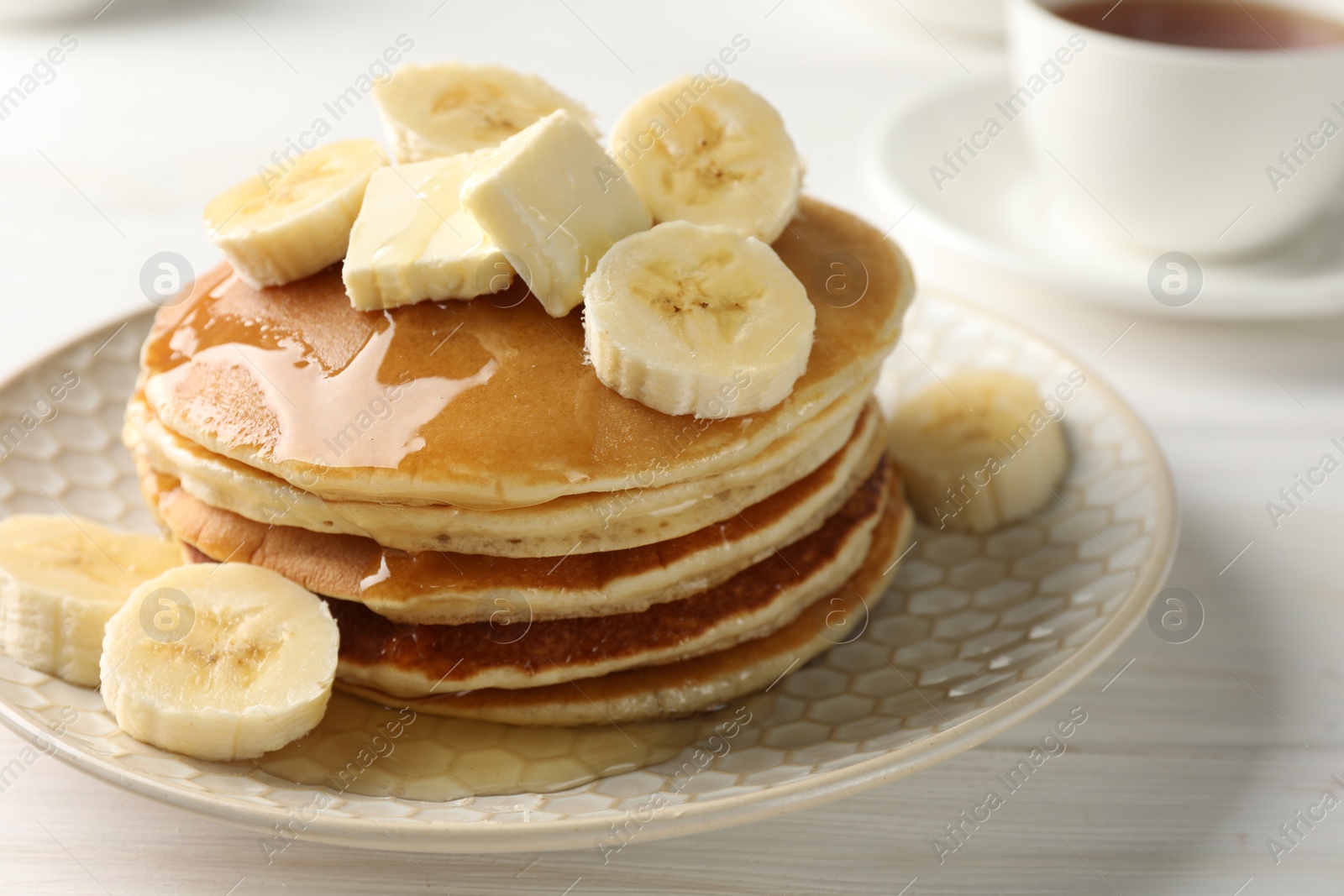 Photo of Delicious pancakes with bananas, honey and butter on white wooden table, closeup