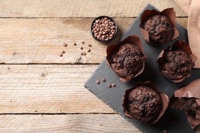 Photo of Delicious chocolate muffins on wooden table, flat lay. Space for text