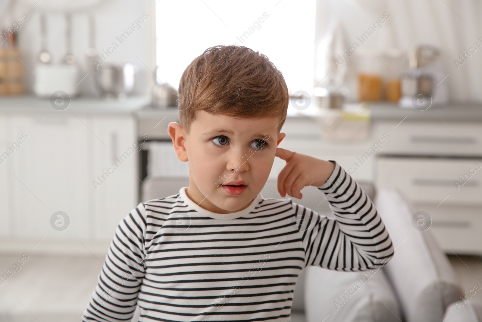 Photo of Little boy picking ear at home. Annoying itch
