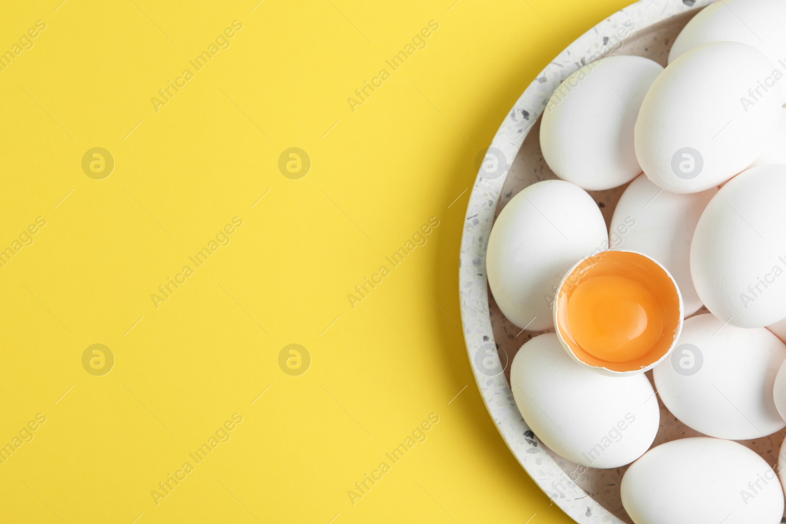 Photo of Fresh raw chicken eggs on yellow background, top view. Space for text