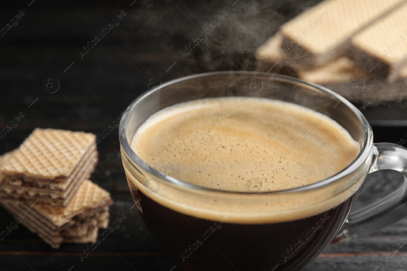 Photo of Delicious coffee and wafers on black table, closeup