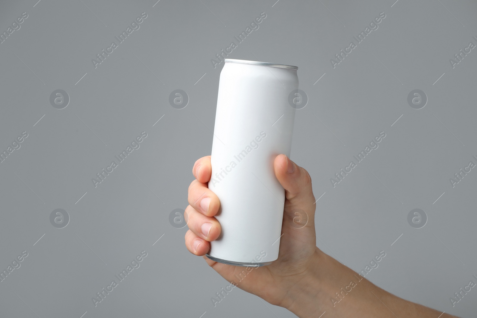 Photo of Man holding aluminum can with beverage on grey background, closeup. Space for design