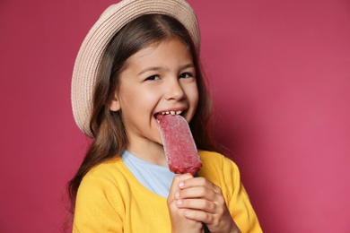 Adorable little girl with delicious ice cream against color background