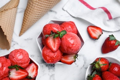 Photo of Yummy strawberry ice cream served on white marble table, flat lay