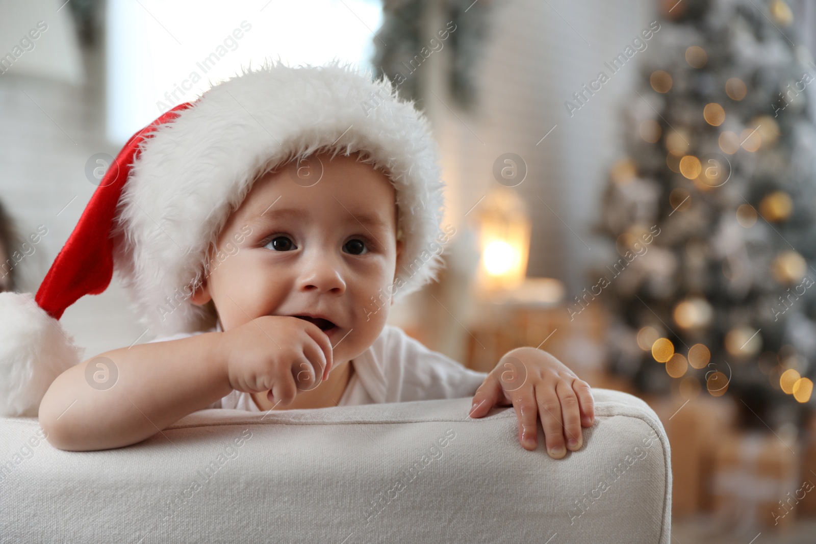 Image of Cute little baby wearing Santa hat at home. Christmas celebration