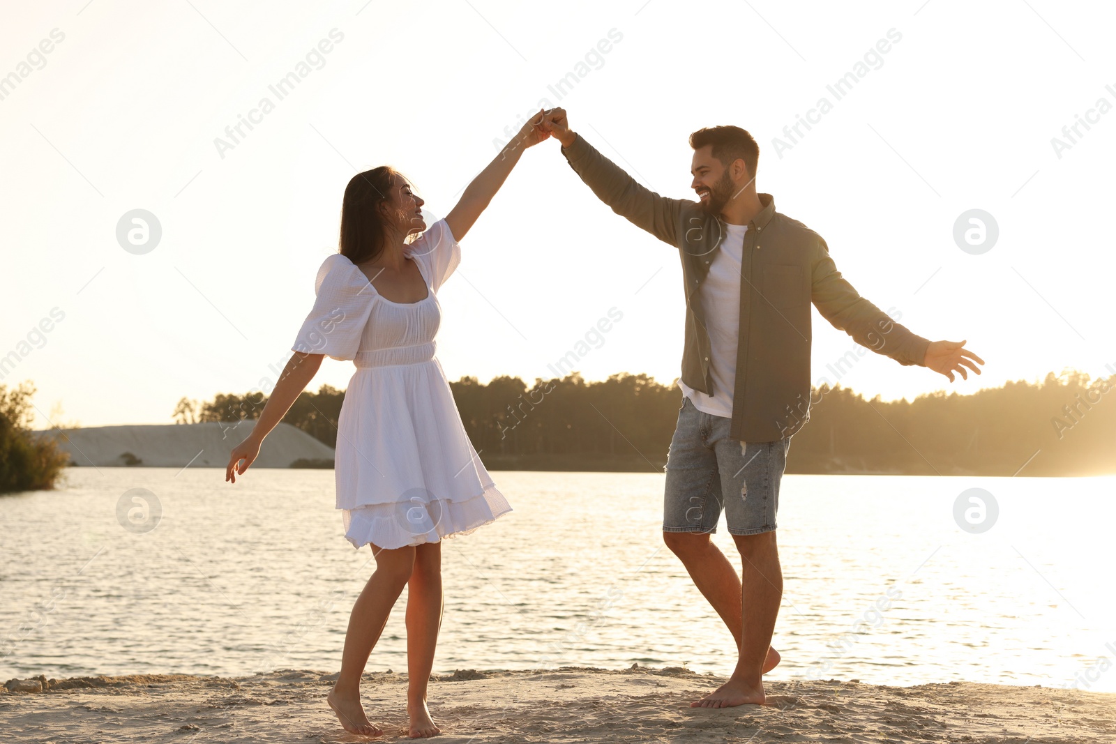 Photo of Happy couple dancing near river on sunny day