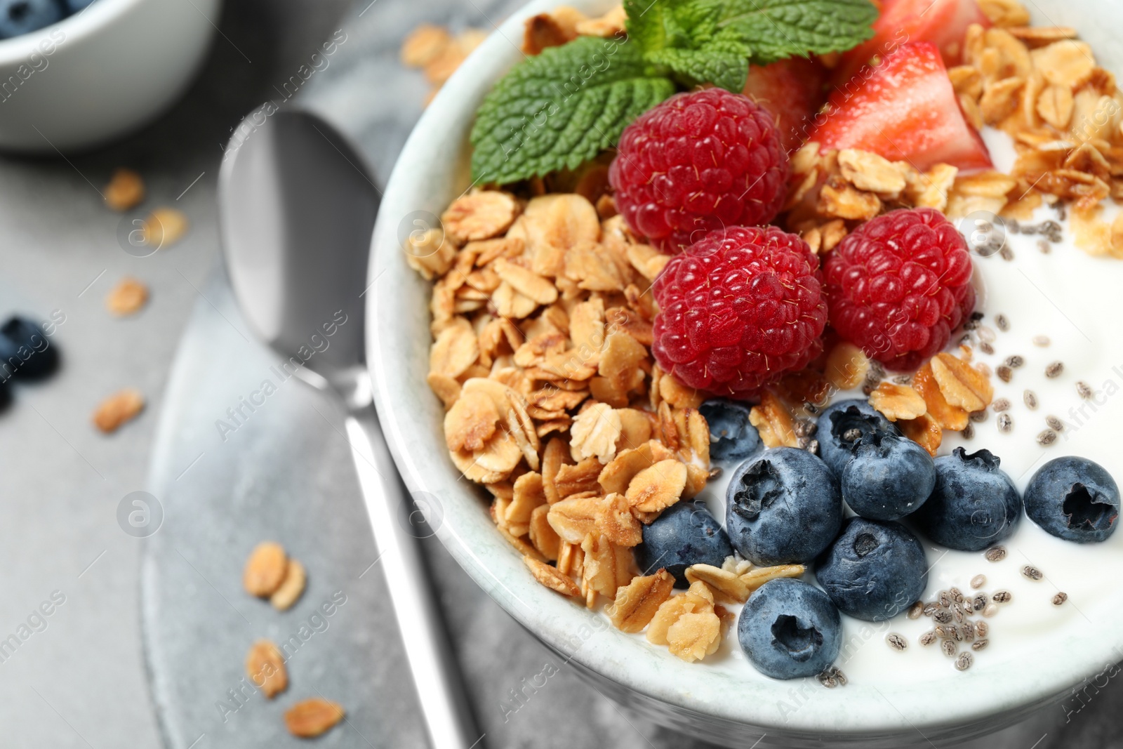Photo of Tasty homemade granola with yogurt and berries on grey table, closeup. Healthy breakfast