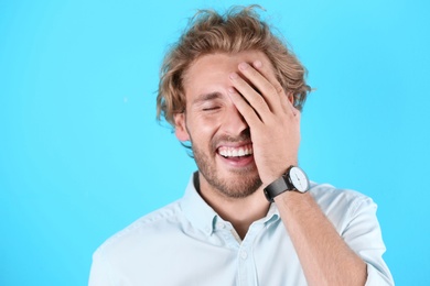 Photo of Handsome young man laughing on color background