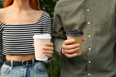 Coffee to go. Couple with paper cups outdoors, closeup