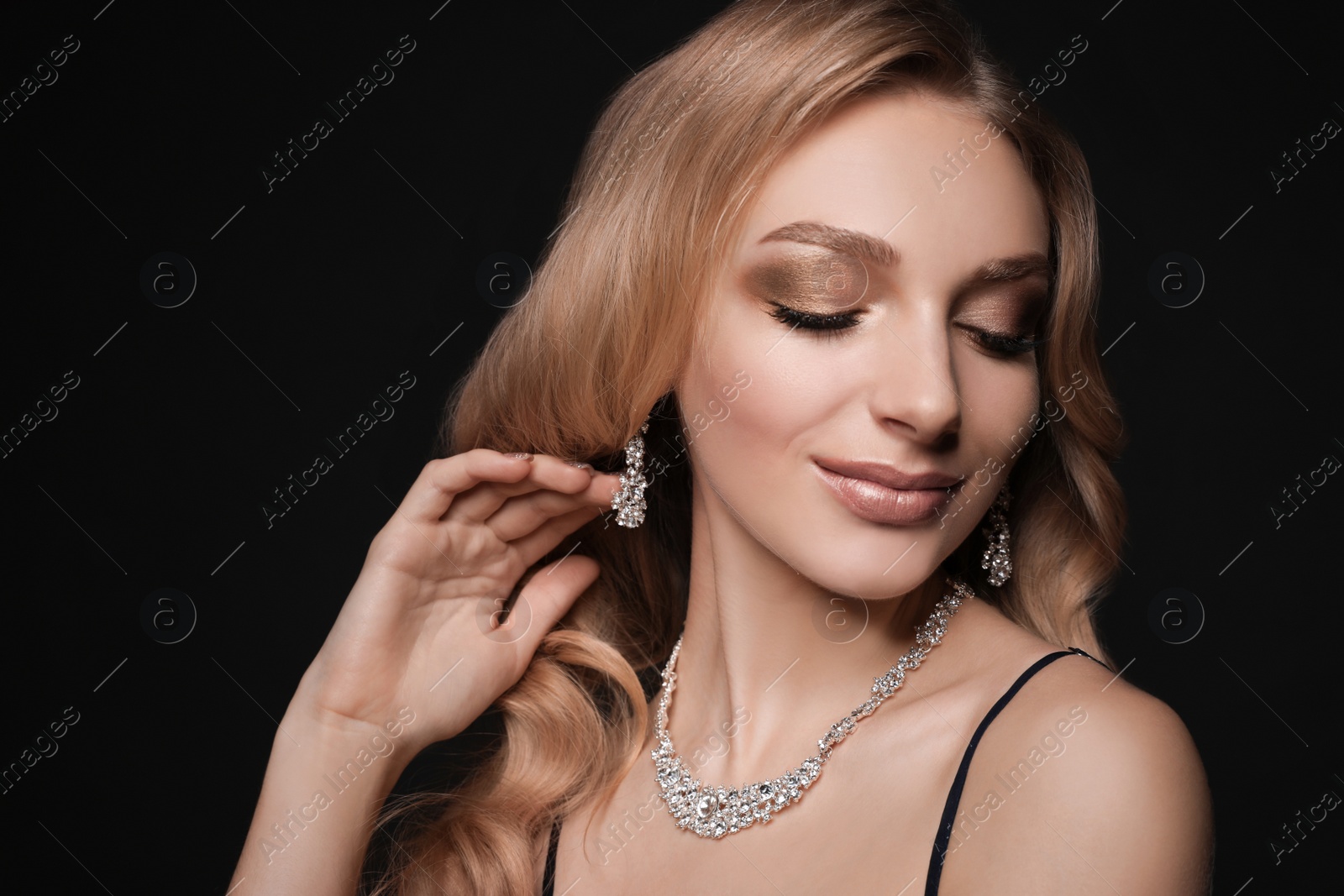 Photo of Beautiful young woman with elegant jewelry on dark background