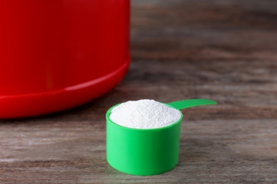 Photo of Scoop of protein powder on wooden table