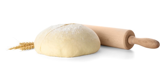 Photo of Raw wheat dough, rolling pin and spikes on white background