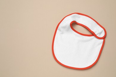 New baby bib on beige background, top view. Space for text