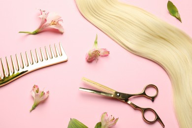 Photo of Hairdresser tools. Blonde hair lock, comb, scissors and flowers on pink background, flat lay