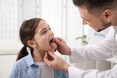 Pediatrician examining little girl in office at hospital