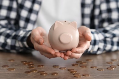 Financial savings. Man with piggy bank at wooden table