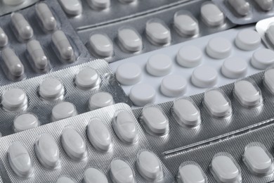 Photo of Many different pills in blisters as background, closeup