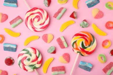 Photo of Many different jelly candies and lollipops on pink background, flat lay