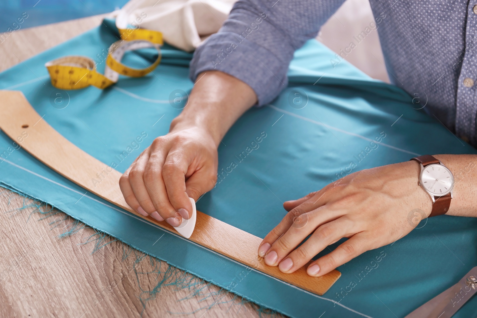 Photo of Tailor working with cloth at table in atelier