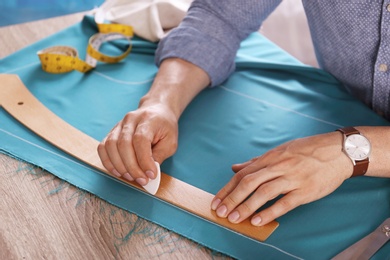 Tailor working with cloth at table in atelier