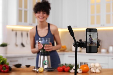 Food blogger recording video in kitchen, focus on smartphone