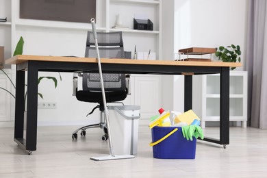 Photo of Cleaning service. Mop and buckets with supplies in office