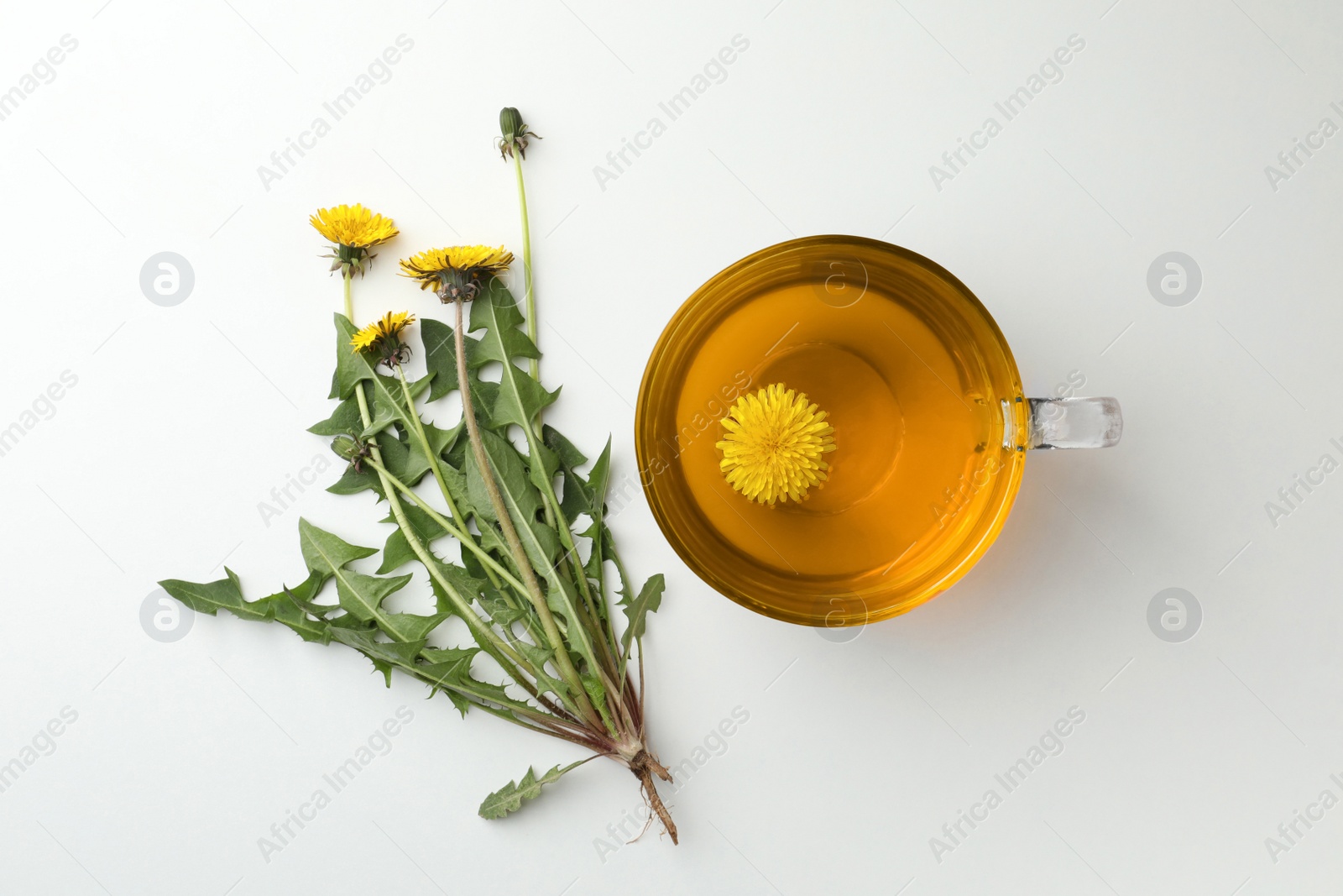 Photo of Delicious fresh tea and beautiful dandelion flowers on white background, top view