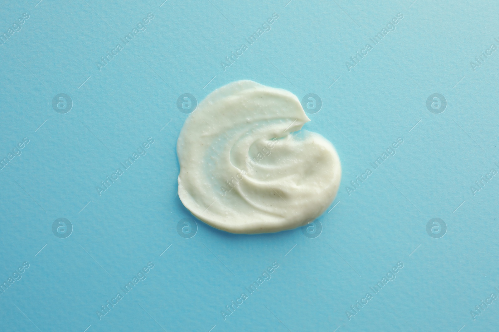 Photo of Sample facial cream on turquoise background, top view