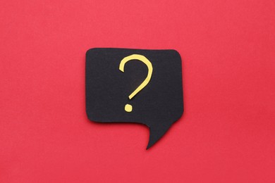 Photo of Paper speech bubble with question mark on red background, top view