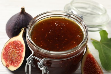 Photo of Glass jar with tasty sweet jam and fresh figs on white table, closeup