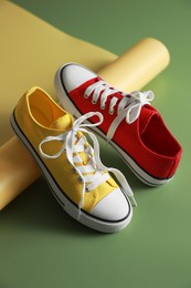 Photo of Stylish presentation of red and yellow classic old school sneakers on green background