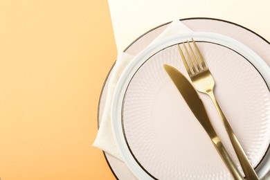 Photo of Ceramic plates, cutlery and napkin on color background, top view. Space for text