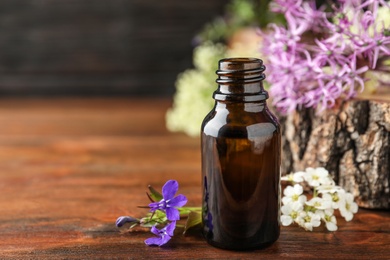 Photo of Bottle of essential oil on wooden table. Space for text