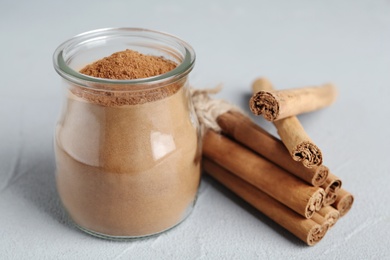 Photo of Aromatic cinnamon powder and sticks on grey table, closeup
