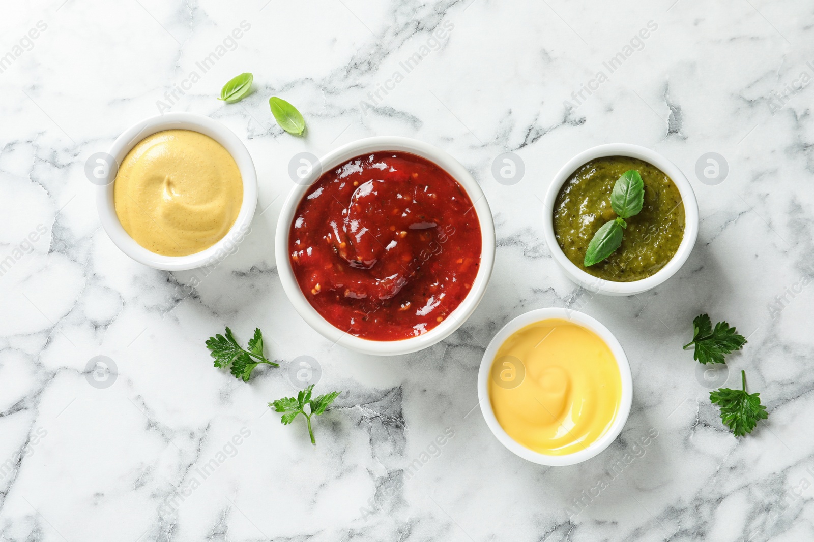 Photo of Set of different delicious sauces on white marble table, top view