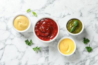 Photo of Set of different delicious sauces on white marble table, top view