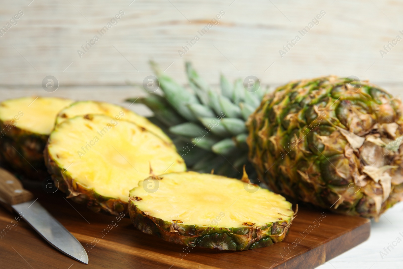 Photo of Slices of fresh pineapple on wooden board, closeup