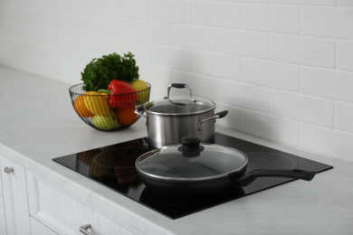 Saucepot and frying pan on induction stove in kitchen