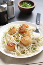 Delicious scallop pasta with green onion served on grey table