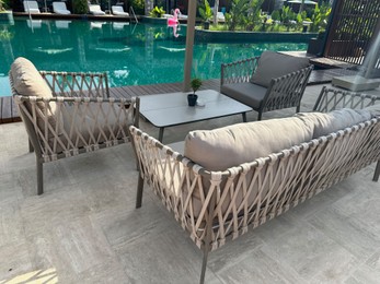 Photo of Cozy outdoor furniture in recreation area near swimming pool