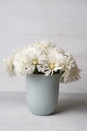 Beautiful chrysanthemum flowers in vase on grey table