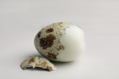Photo of One boiled quail egg in shell on white table, closeup