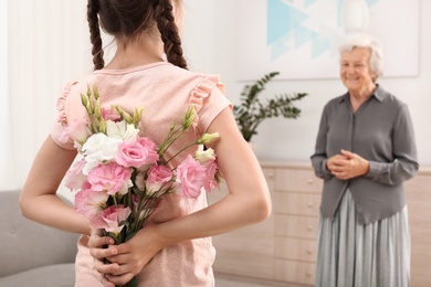Photo of Girl congratulating her grandmother at home, closeup