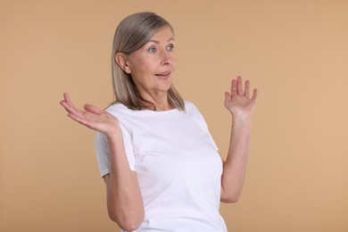 Portrait of surprised senior woman on beige background