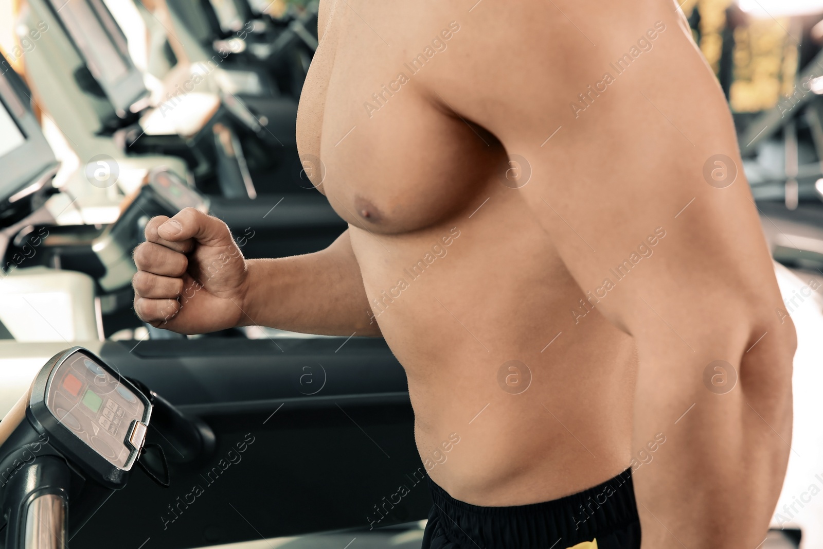Photo of Strong young man on treadmill in gym, closeup of torso