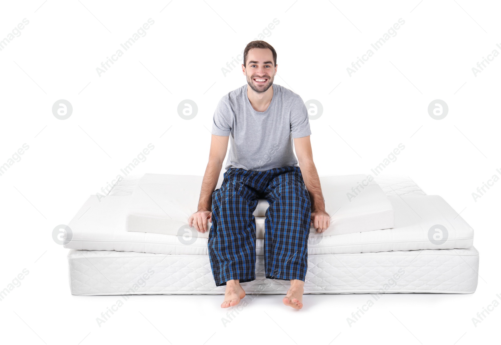 Photo of Young man sitting on mattress pile against white background