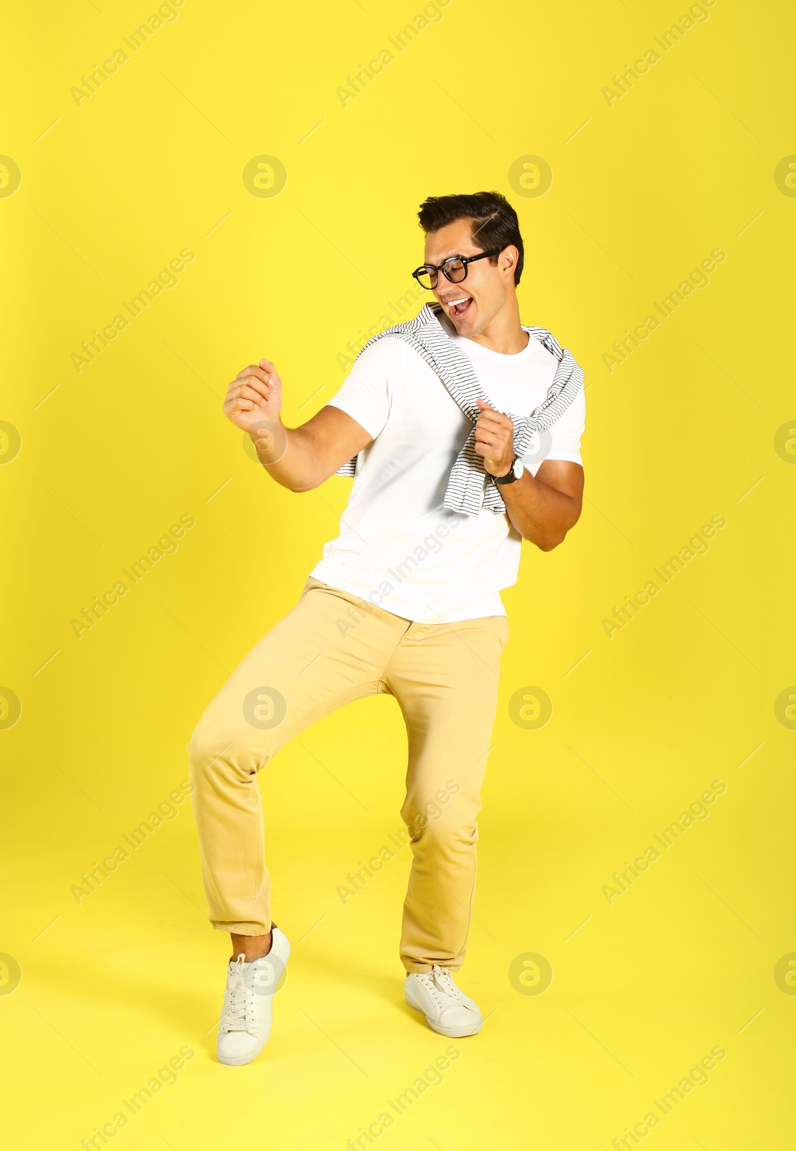 Photo of Handsome young man dancing on yellow background